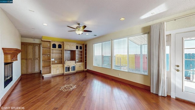 unfurnished living room with dark hardwood / wood-style floors and ceiling fan