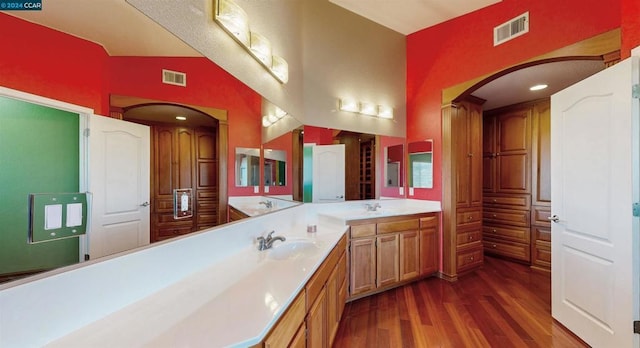 bathroom featuring hardwood / wood-style floors, vanity, and lofted ceiling