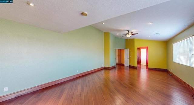 spare room featuring a textured ceiling, ceiling fan, wood-type flooring, and lofted ceiling