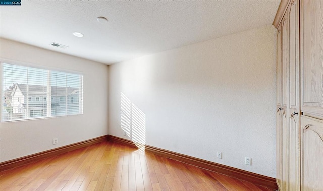 unfurnished room featuring a textured ceiling and hardwood / wood-style flooring