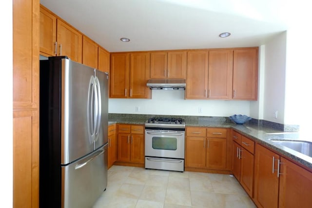 kitchen with stainless steel appliances, dark stone counters, and sink