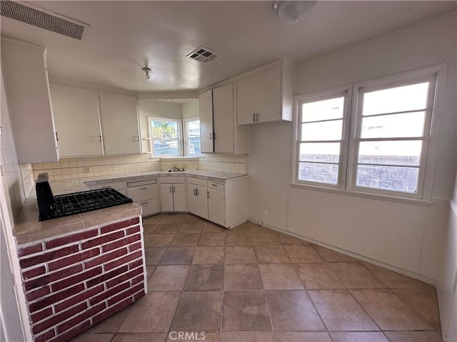 kitchen with tasteful backsplash, sink, white cabinets, and light tile patterned floors