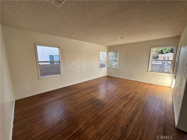 empty room with a textured ceiling and dark wood-type flooring