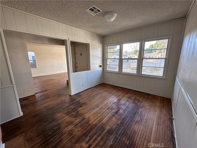 unfurnished room with a textured ceiling and dark hardwood / wood-style floors