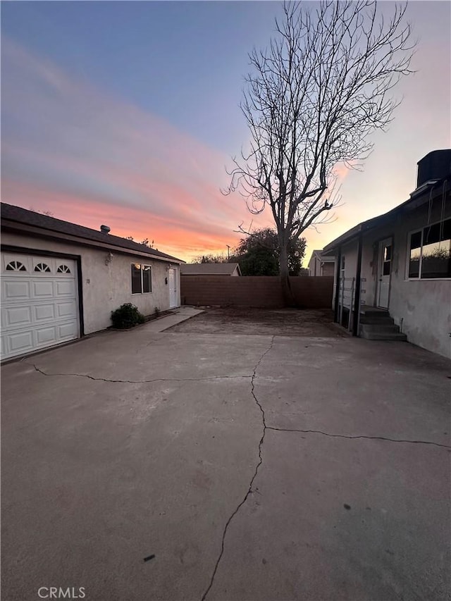 patio terrace at dusk featuring a garage