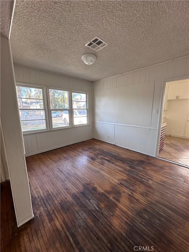 unfurnished room featuring a textured ceiling and dark wood-type flooring