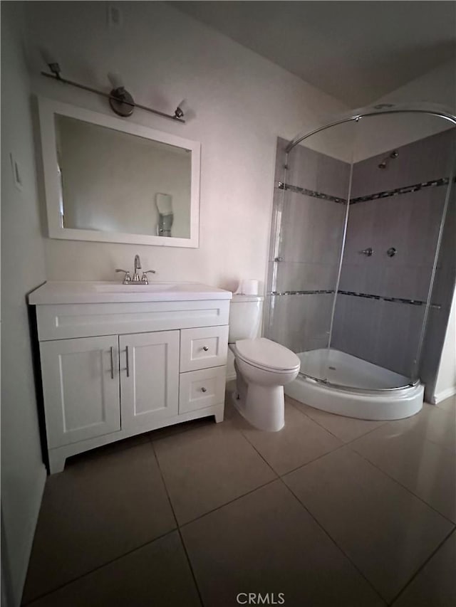 bathroom with toilet, a tile shower, vanity, and tile patterned floors