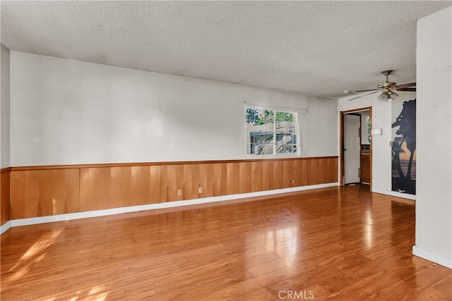 empty room with hardwood / wood-style floors, ceiling fan, and a textured ceiling