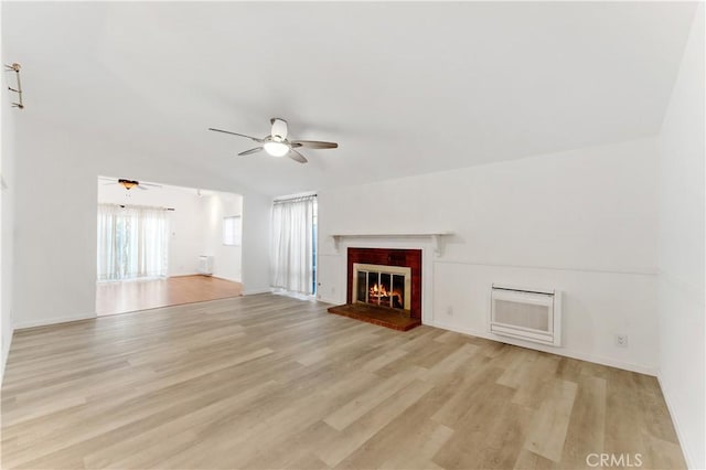 unfurnished living room with lofted ceiling, ceiling fan, a fireplace, light hardwood / wood-style floors, and heating unit