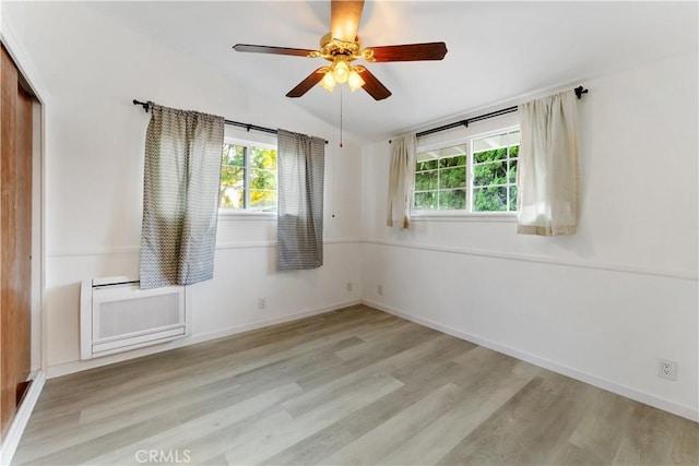 spare room with light hardwood / wood-style flooring, vaulted ceiling, and ceiling fan