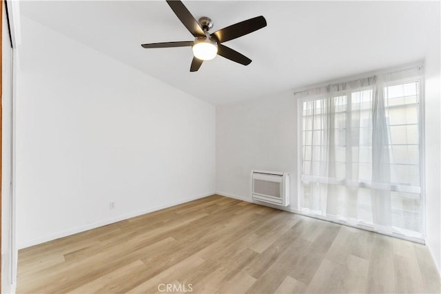 unfurnished room featuring ceiling fan, light wood-type flooring, and heating unit