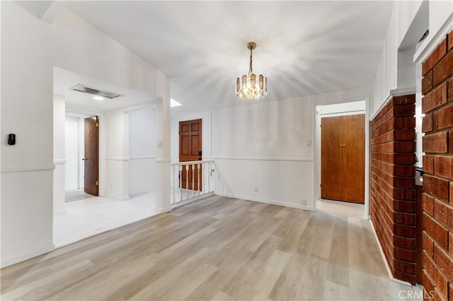 empty room with light hardwood / wood-style flooring and a notable chandelier