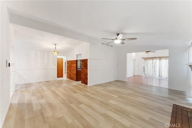 unfurnished living room with ceiling fan with notable chandelier, light wood-type flooring, and lofted ceiling