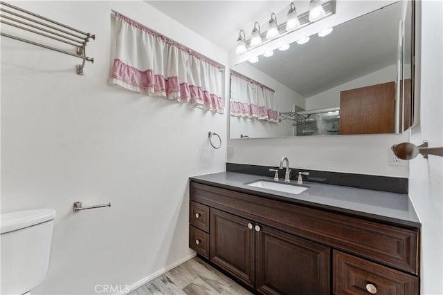 bathroom featuring wood-type flooring, an enclosed shower, lofted ceiling, toilet, and vanity