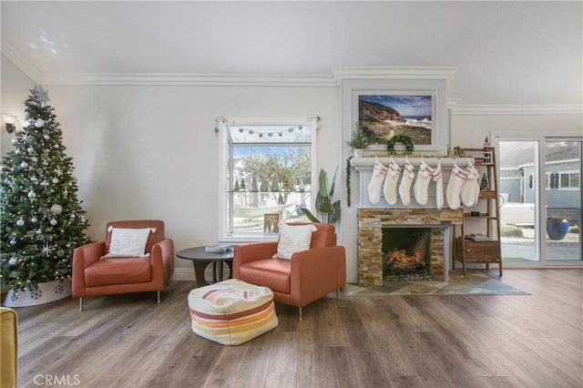 living area featuring hardwood / wood-style flooring, a stone fireplace, and crown molding