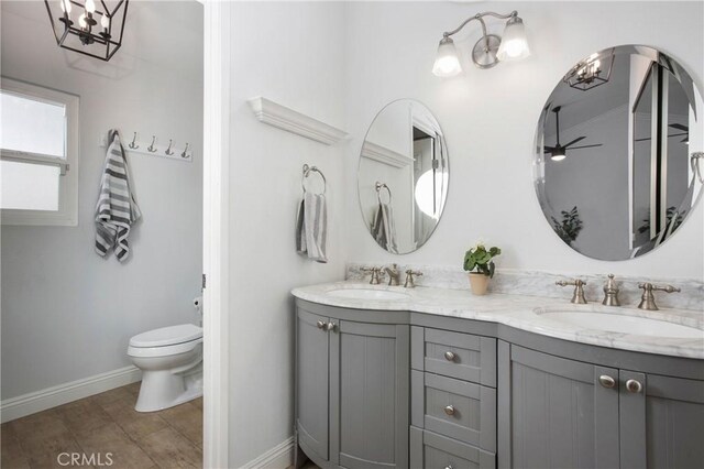 bathroom with wood-type flooring, vanity, toilet, and ceiling fan