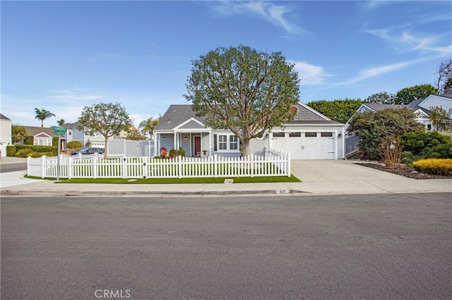 view of front of house featuring a garage, concrete driveway, and a fenced front yard