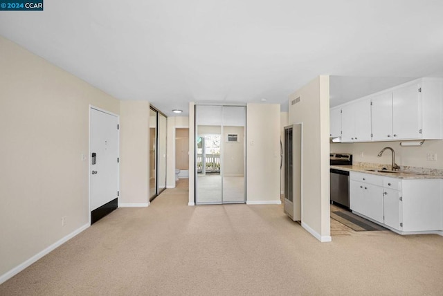 kitchen featuring light carpet, white cabinets, dishwasher, and sink