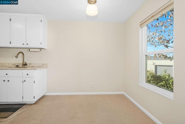 bar with light carpet, white cabinets, and sink