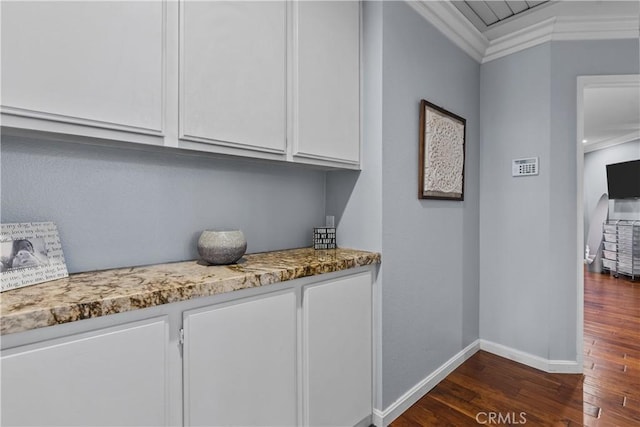 bar featuring white cabinets, dark wood-type flooring, light stone counters, and ornamental molding