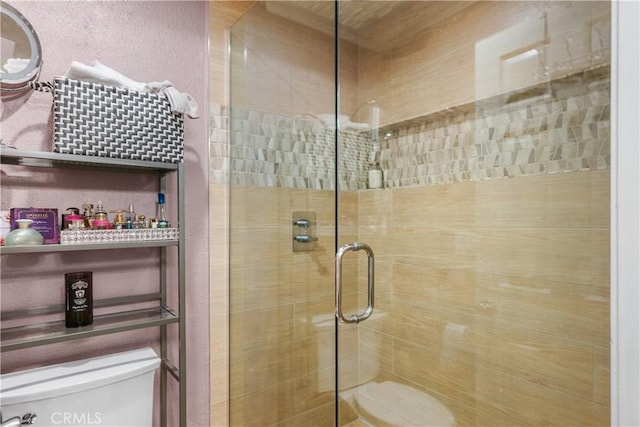 bathroom with toilet and a shower with shower door