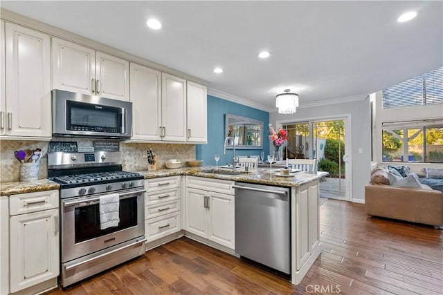 kitchen with white cabinetry, dark wood-type flooring, stainless steel appliances, backsplash, and kitchen peninsula