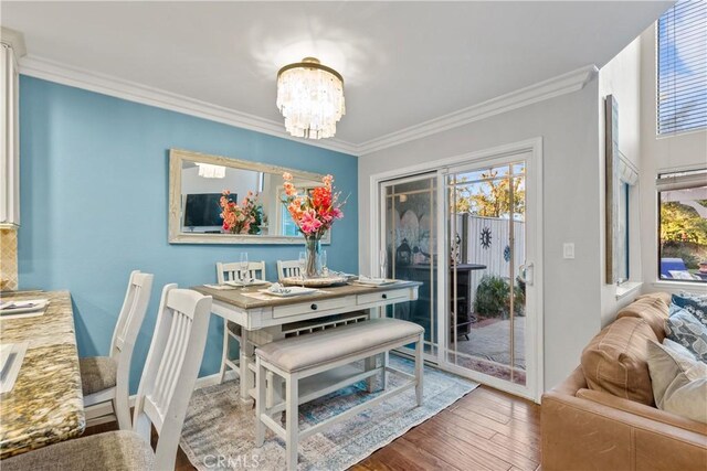 dining room with hardwood / wood-style flooring, crown molding, and a notable chandelier