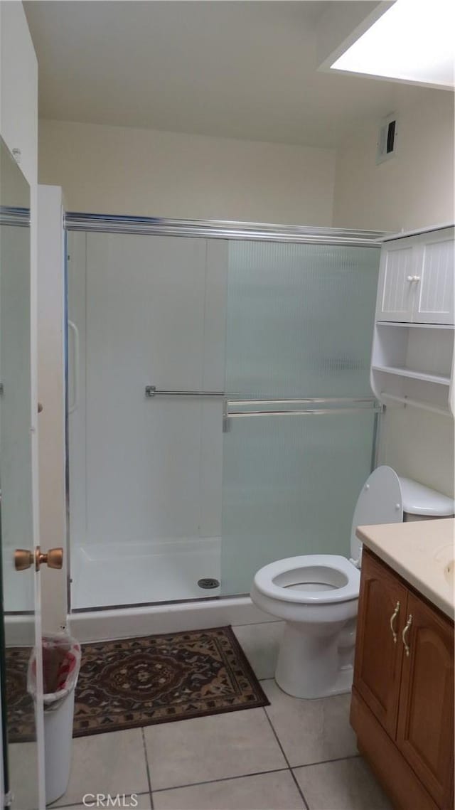 bathroom featuring walk in shower, vanity, tile patterned floors, and toilet