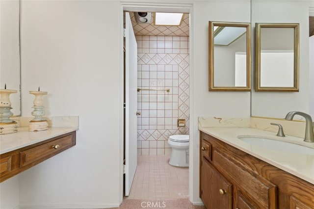 bathroom featuring tiled shower, tile patterned flooring, vanity, and toilet