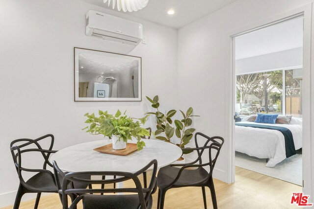 dining area featuring a wall mounted AC and light hardwood / wood-style flooring