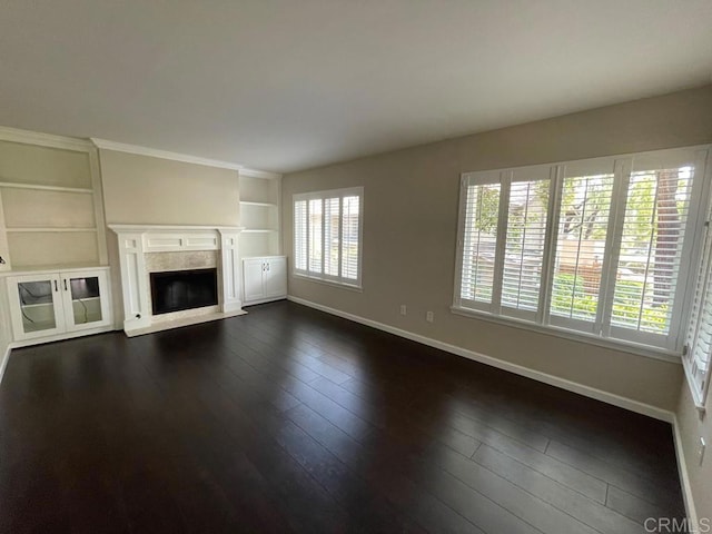 unfurnished living room with built in shelves and dark wood-type flooring