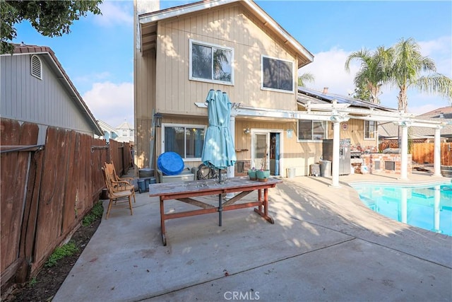 back of house with solar panels, a patio area, and a fenced in pool