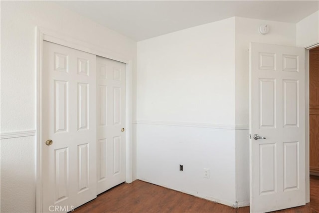 unfurnished bedroom with dark wood-type flooring and a closet