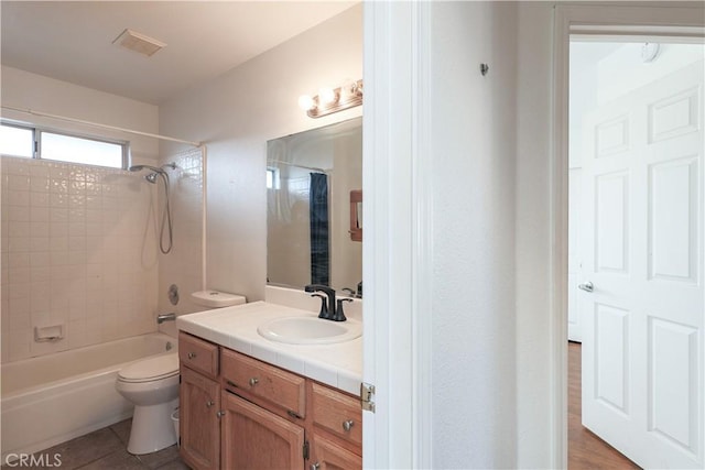 full bathroom featuring hardwood / wood-style flooring, vanity, tiled shower / bath combo, and toilet