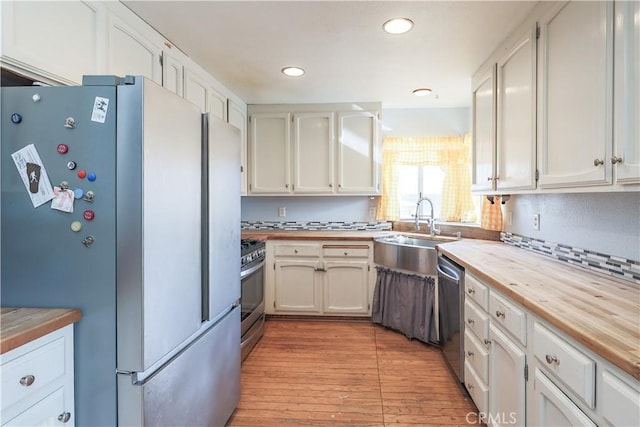 kitchen featuring white cabinetry, sink, stainless steel appliances, wooden counters, and light wood-type flooring