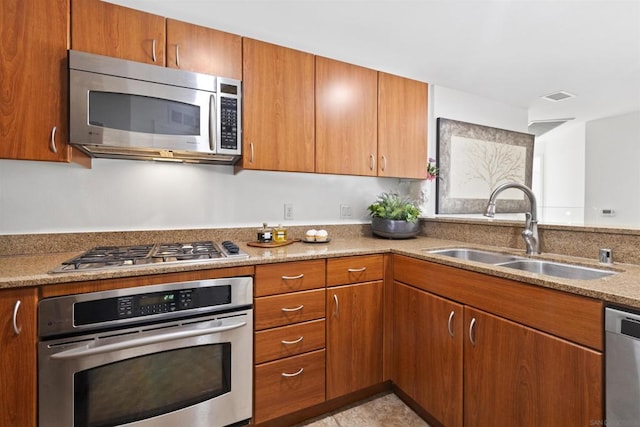 kitchen featuring appliances with stainless steel finishes, light stone counters, and sink