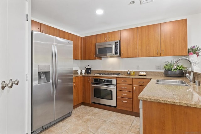 kitchen featuring light tile patterned floors, stainless steel appliances, light stone counters, and sink