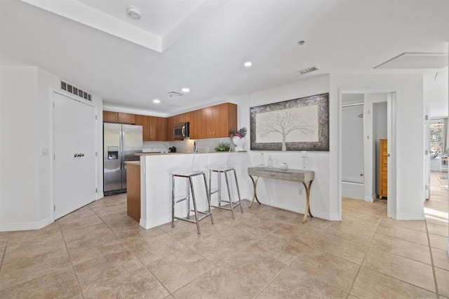 kitchen with a breakfast bar, light tile patterned floors, kitchen peninsula, and appliances with stainless steel finishes