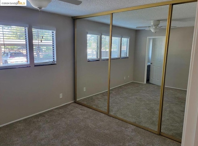 unfurnished bedroom with ceiling fan, a closet, carpet floors, and multiple windows