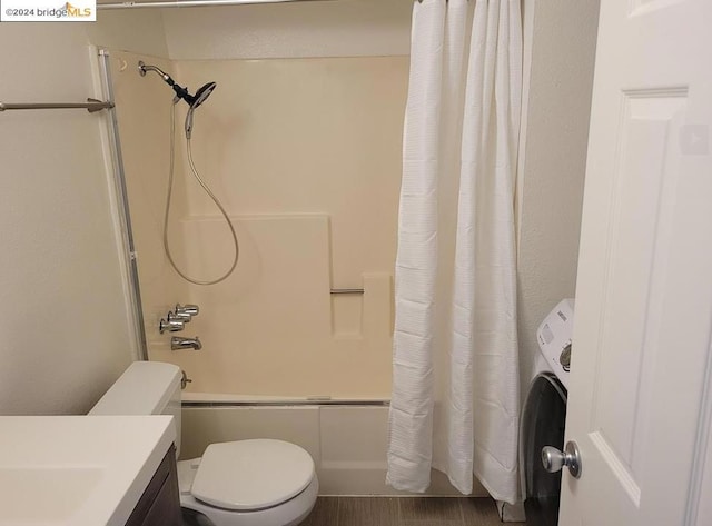 bathroom featuring washer / dryer, shower / tub combo, toilet, and wood-type flooring