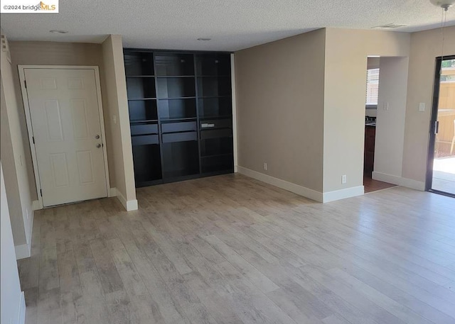 unfurnished room featuring a textured ceiling and light hardwood / wood-style flooring