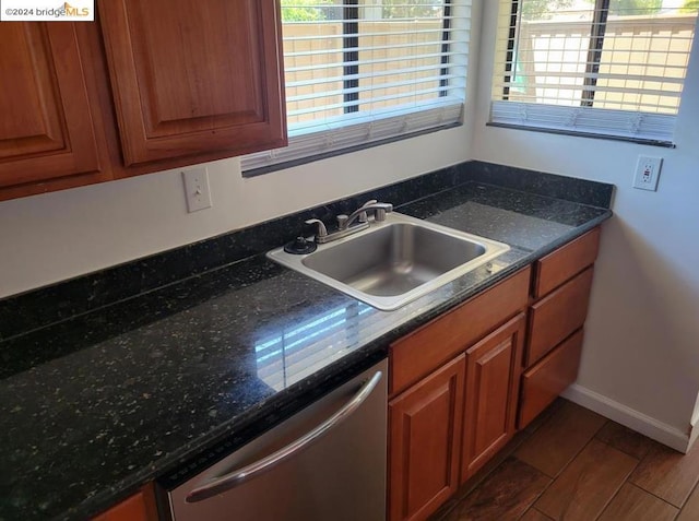 kitchen featuring stainless steel dishwasher, dark stone countertops, and sink