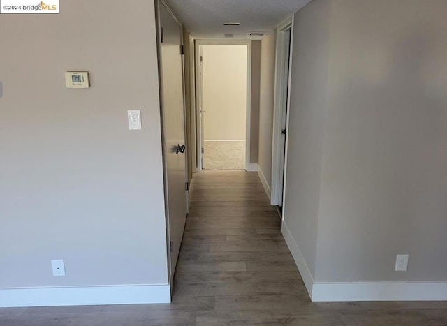 corridor featuring hardwood / wood-style floors and a textured ceiling