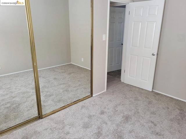 unfurnished bedroom featuring light carpet and a closet