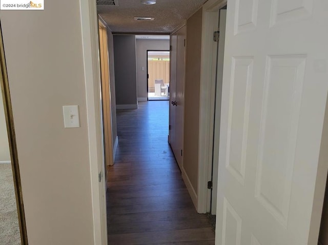 corridor with dark hardwood / wood-style flooring and a textured ceiling