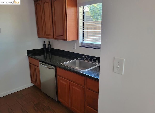 kitchen featuring dark hardwood / wood-style floors, stainless steel dishwasher, dark stone counters, and sink