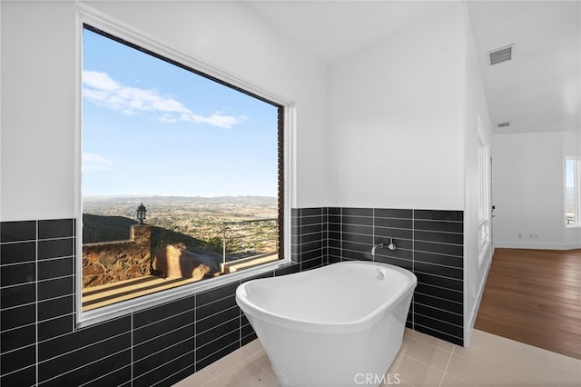 bathroom with a washtub, tile patterned flooring, and tile walls