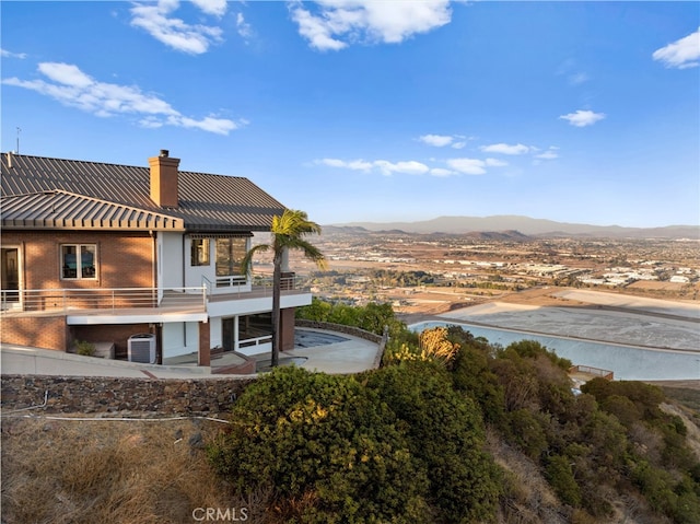 rear view of house with a mountain view and a balcony