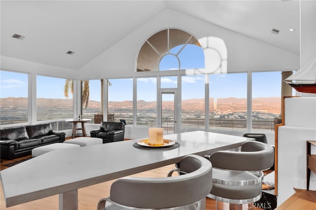 dining room with a mountain view, light hardwood / wood-style floors, and high vaulted ceiling