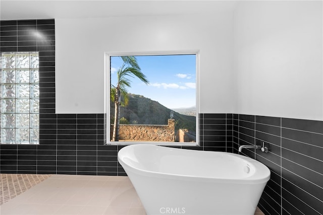 bathroom with a mountain view, tile patterned flooring, tile walls, and a bathing tub